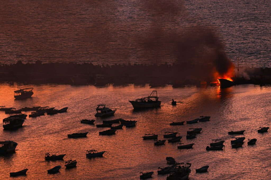 Embarcación en llamas tras uno de los ataques israelíes contra el puerto de Gaza. Fuente - Mahmud Hams (AFP).