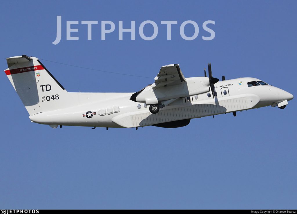 De Havilland Canada E-9A Widget despegando. Nótese la prominente antena para efectuar el seguimiento de los misiles y el radar de vigilancia marítima (radomo negro en la parte inferior)